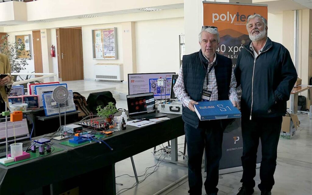 Two men standing in front of a technological products display bench
